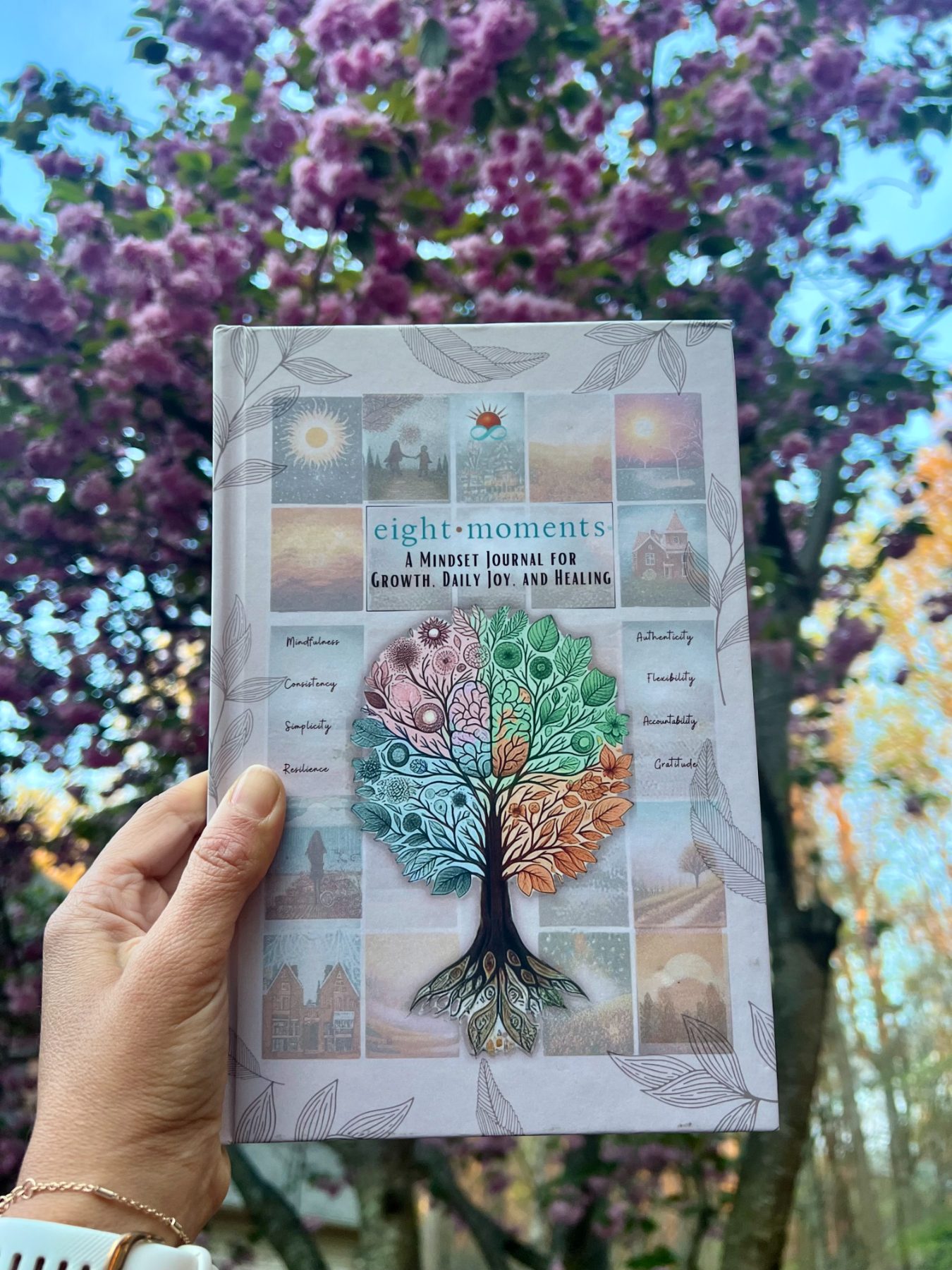 The journal held up beneath cherry blossoms in full spring bloom