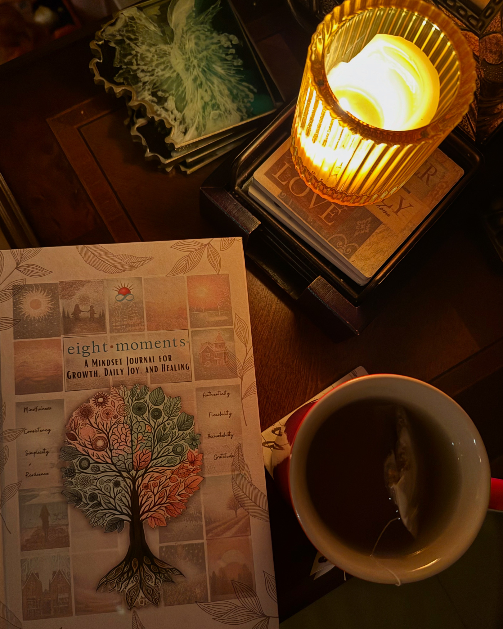The journal on a wooden table by candlelight beside a warm cup of tea