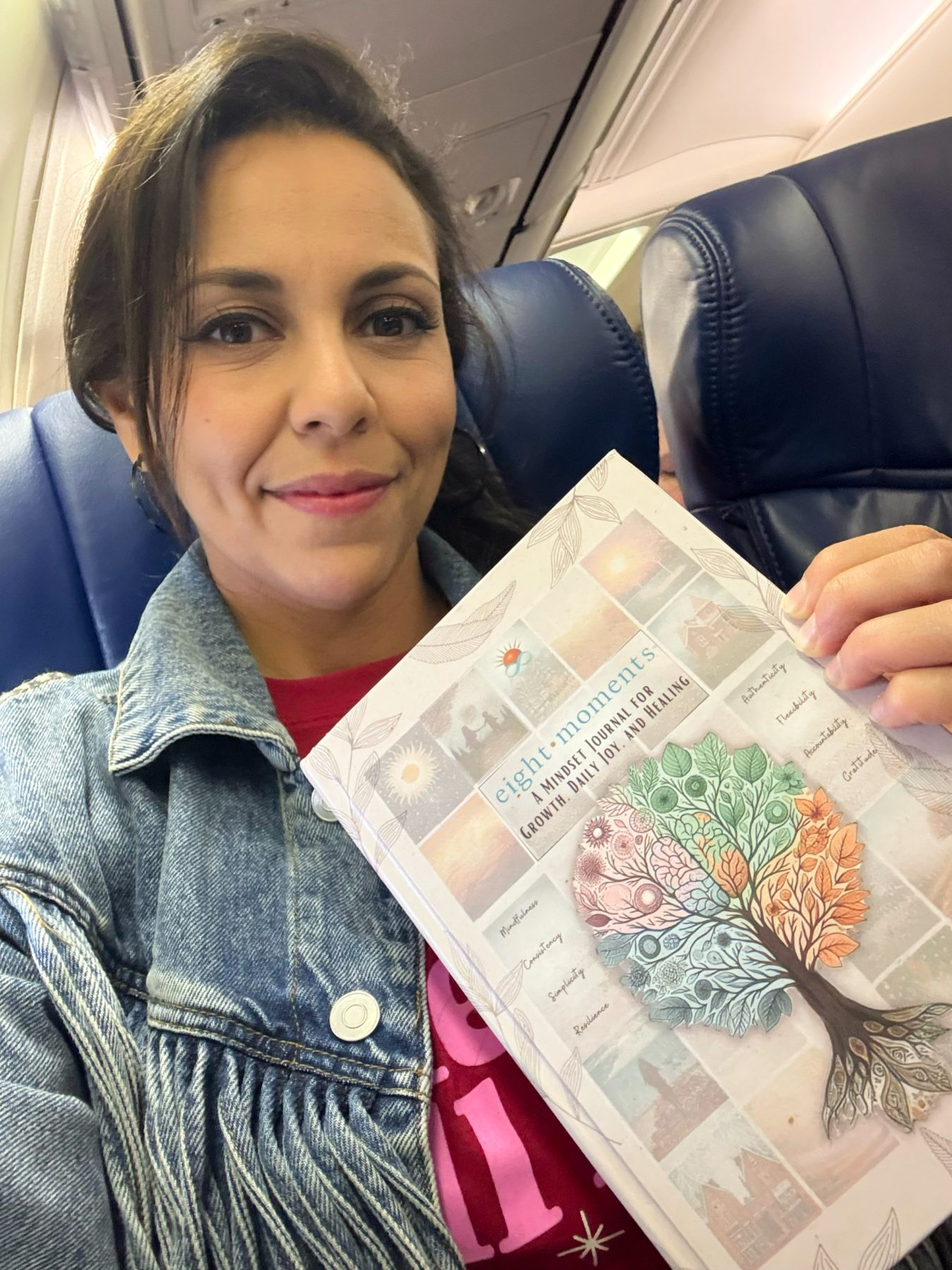 Heba holding the journal on an airplane