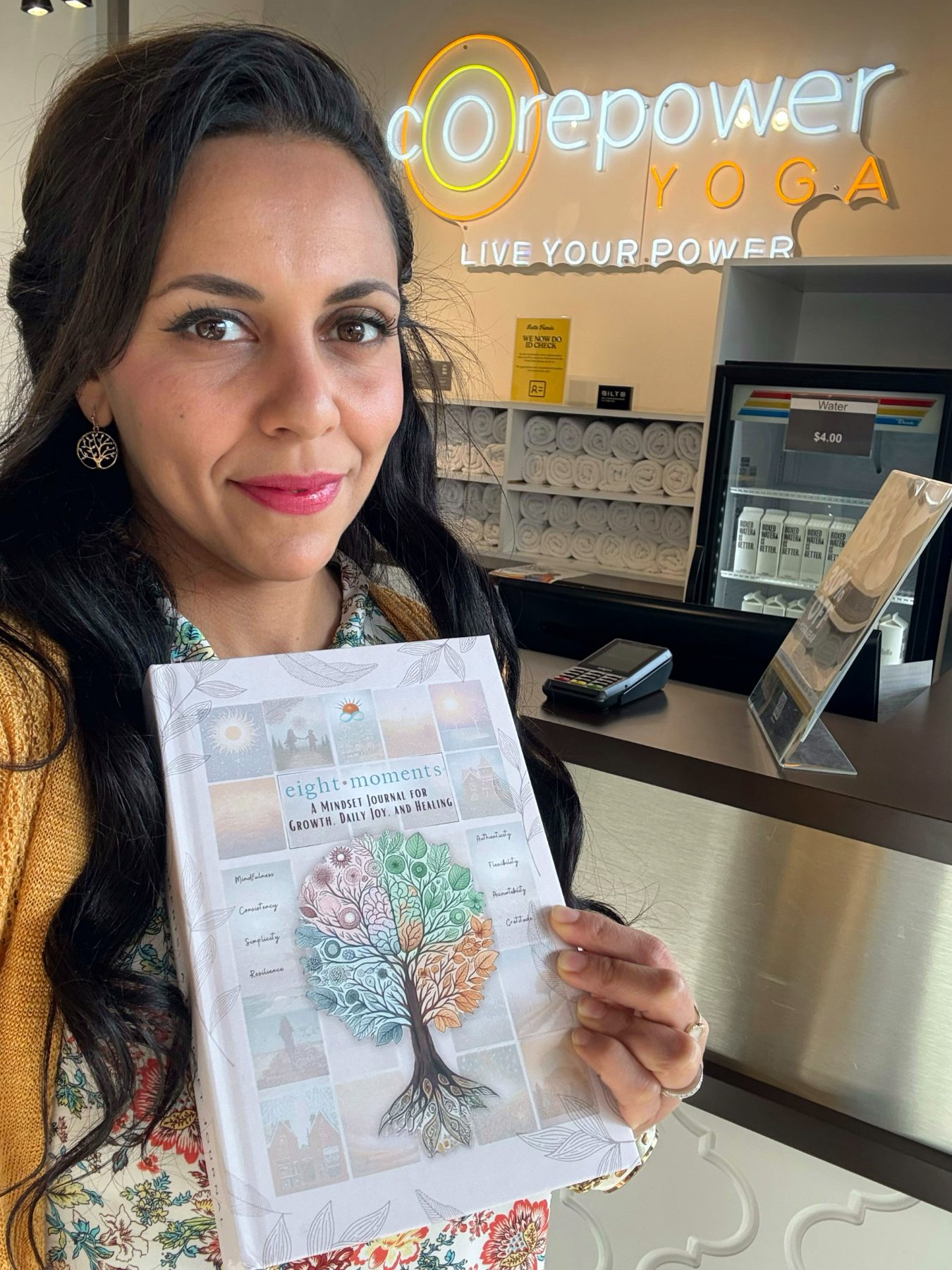 Heba holding the journal at a yoga studio front desk