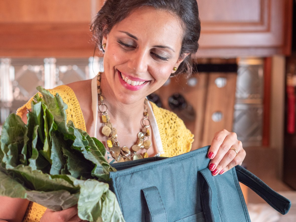 Heba smiling as she unpacks fresh greens in her kitchen