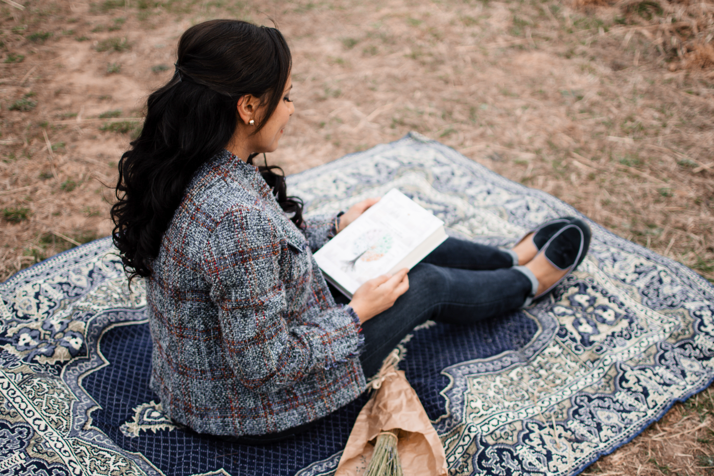 Heba reading the Eight Moments journal on a blanket outdoors